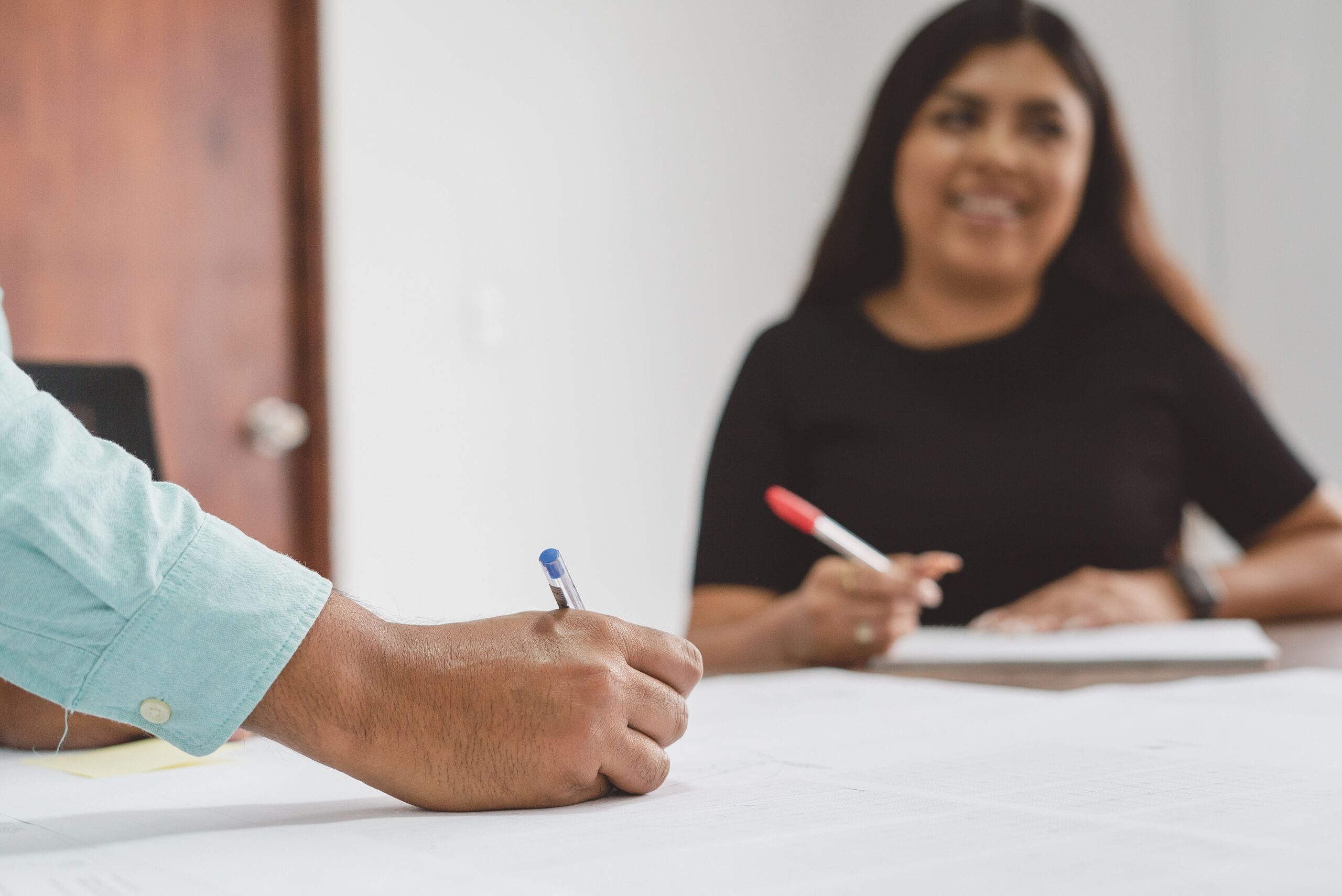 Two professionals engaged in a business meeting. One writes notes while the other attentively listens.